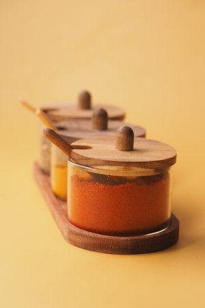 Spices in glass containers on a wooden tray