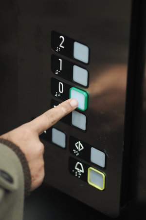 Person presses button in an elevator to go down