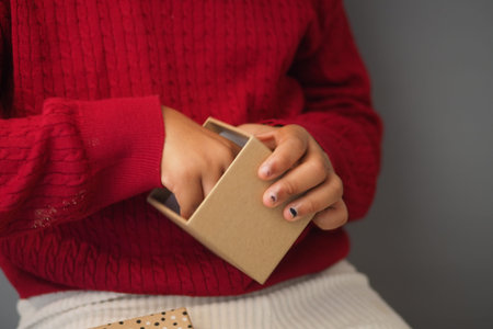 Child opens small box with hands in indoor setting
