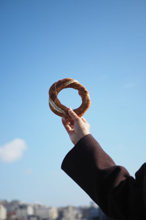 Hand holds turkish simit against clear sky