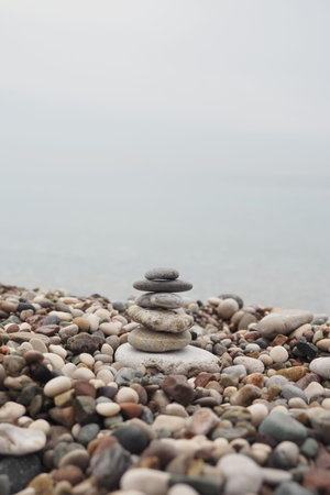 Stone tower on pebbled beach near calm water