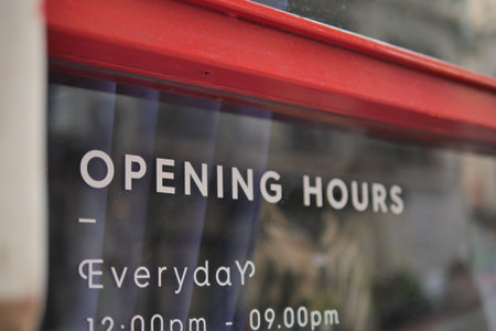 Store hours displayed on a shop window in the city