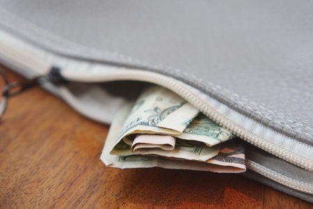 Money tucked inside a bag on a wooden table surface