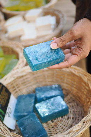 Hand holds blue soap bar in market basket