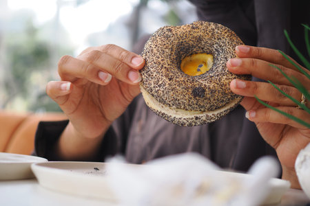 Enjoying a delicious bagel with poppy seeds in a cozy cafe