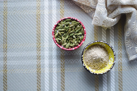 Cardamom Pods and Ground Cardamom in Colorful Bowls on Rustic Tablecloth