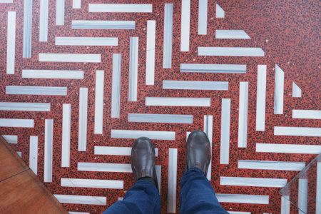 Footwear on a patterned floor with red and white tiles in a building