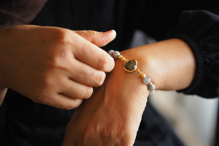 Woman wearing a bracelet with stones on her wrist in a blurred background