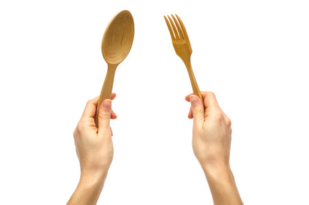 hand of young girl holding spoon and fork. Isolated on white background
