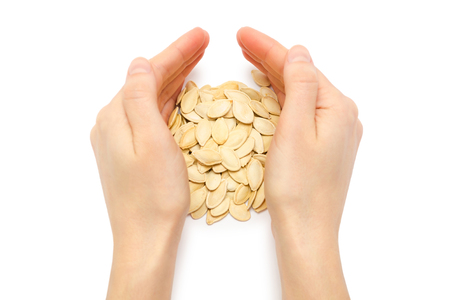 female hand takes or gives pumpkin seeds. Isolated on white backgroundの写真素材