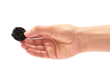 female hand holds dry prunes. isolated on white backgroundの写真素材