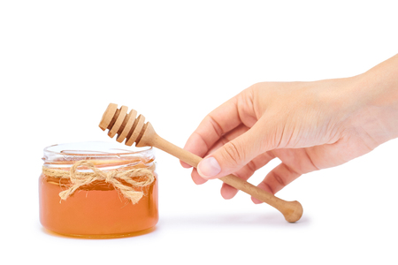 Hand holding honey jar isolated on white background.の写真素材