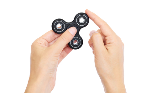 Hand holding Black Fidget Spinner isolated on white background.の写真素材