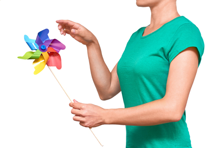 Girl hands turning paper wind mill. Isolated on white background.の写真素材
