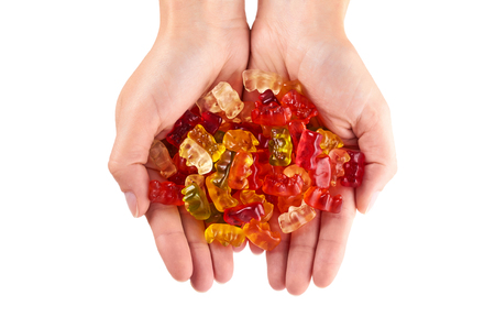 Childhood and jelly bears candies in hand isolated on white background.の写真素材