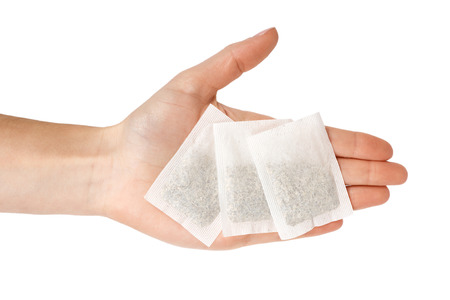 Tea in paper bag in hand. Isolated on white background. Herbal teabag.の写真素材