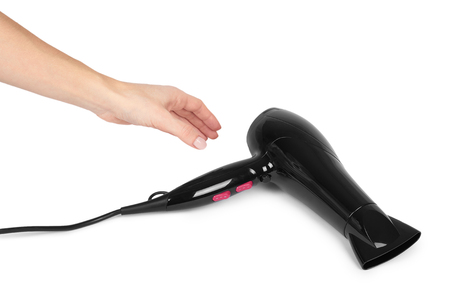 Black plastick hair dryer with pink buttons in hand. Isolated on white background. Home appliance, heat air blower for salon.の写真素材