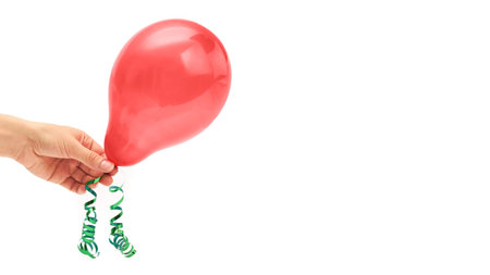 Female hand holds single red party balloon. isolated on white background.の写真素材