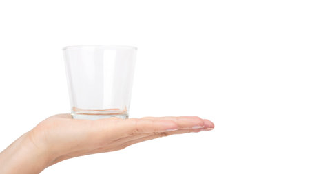 female hand holding transparent glass cup. Isolated on white background. copy space, template.の写真素材