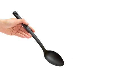female hand holding a black plastic spoon for cooking food. Isolated on white background. copy space, templateの写真素材