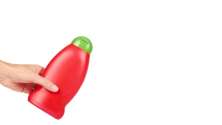 Red plastic bottle for shampoo in hand isolated on white background. Hydiene and cleaning idea. copy space, template.の写真素材