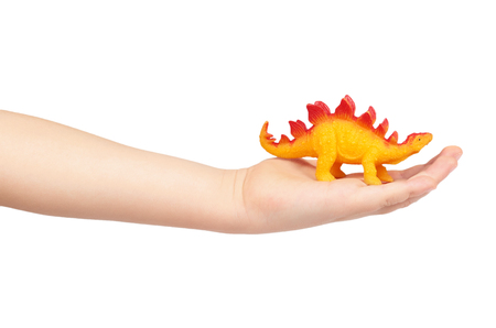 Prehistoric dinosaur rubber toy with kid hand, isolated on white background.の写真素材
