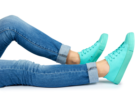 Female leg in jeans and sneakers isolated on white background.の写真素材