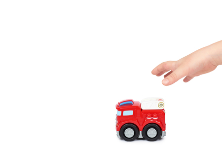 Red toy firefighter car with kid hand, isolated on white background, fire truck engine. copy space template.の写真素材
