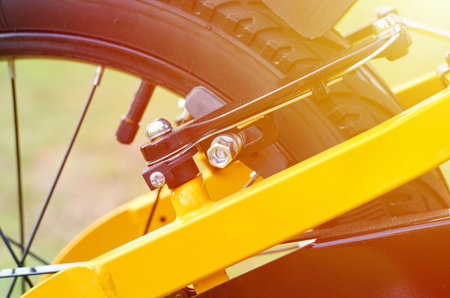 Kids yellow bicycle in park, close up parts, rear tire with brakes, sunlight effect.の写真素材