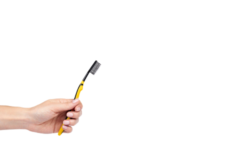Black and yellow soft toothbrush with hand isolated on white background, copy space template.の写真素材