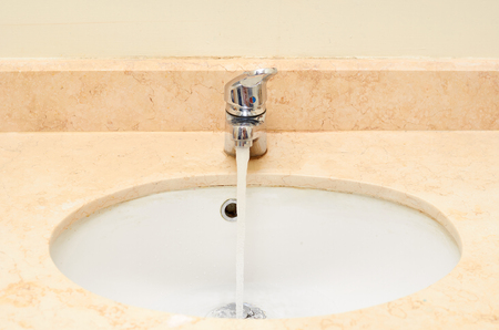 marble sink with chromed faucet, bathroom background.の写真素材