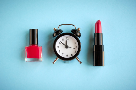 Black alarm clock composition with cosmetics on blue background, flat lay and top view photoの写真素材