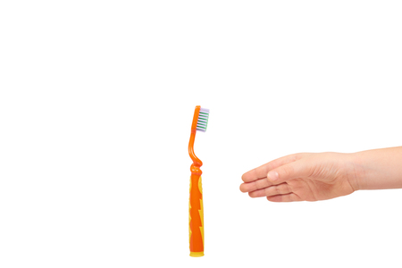 Kids hand with orange toothbrush, dental care concept. Isolated on white background. Copy spaceの写真素材
