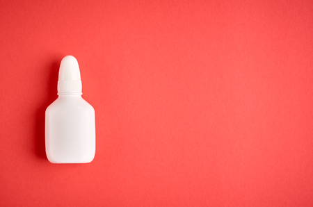 Nasal spray bottle composition, white template bottle on pink background, flat lay and top view photoの写真素材