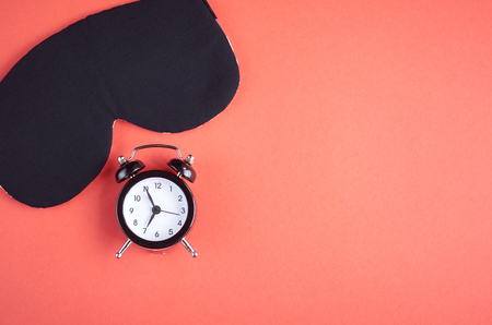 Black sleep mask with clock on pink background composition, cat mask with ears, flat lay and top view photoの写真素材