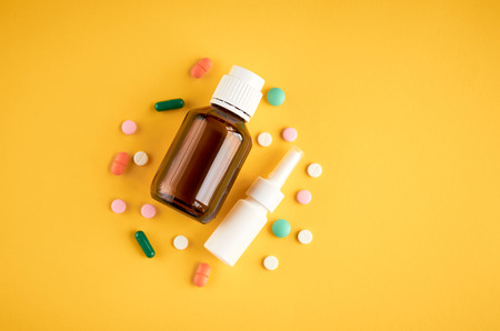 Nasal spray bottle with pills composition, white template bottle on yellow background, flat lay and top view photoの写真素材