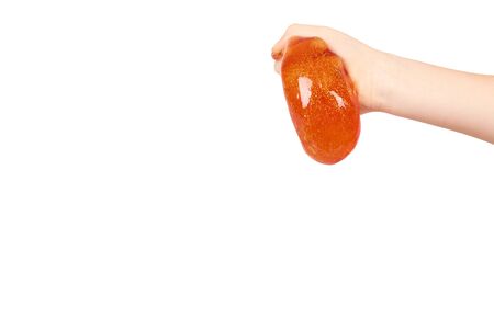 kid playing orange slime with hand, transparent toy. Isolated on white background. Copy space templateの写真素材