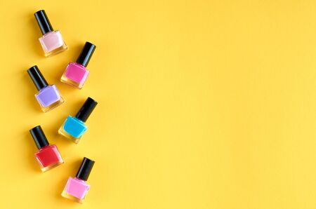 Color nail polish bottles on yellow background composition. Flat lay and top view photoの写真素材