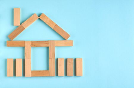 Brown wooden blocks house shape idea on blue background composition. Flat lay and top view photoの写真素材