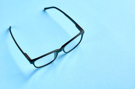 Black glasses on blue background composition, eyeglasses. Flat lay and top view photoの写真素材