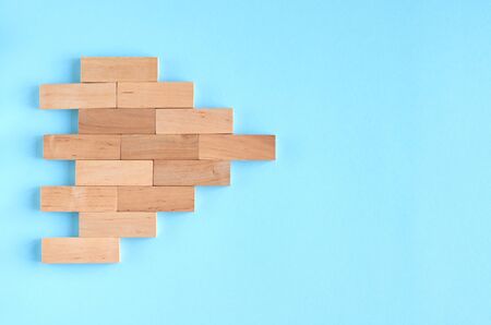 Brown wooden blocks ship or arrow idea on blue background composition. Flat lay and top view photoの写真素材