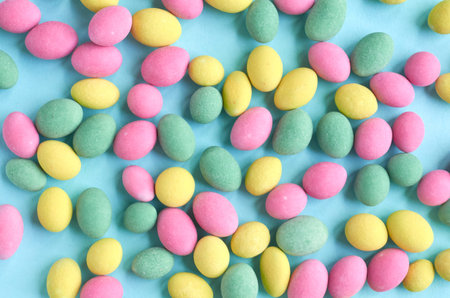 Colored sweets, peanut covered with glaze on blue background composition. Flat lay and top view...