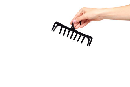 Hand with black plastic clothes hanger. Isolated on white background. Copy space template.