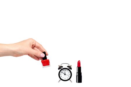 Hand with red nail polish, lipstock and alarm clock. Isolated on white background. Copy space template.の写真素材