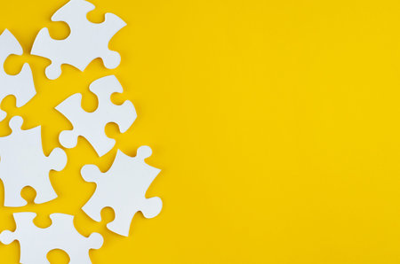 White puzzles composition on yellow background. Flat lay, layout and tabletop mockup with copy...