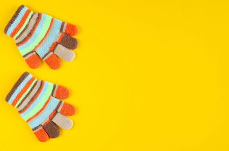 Striped kids winted gloves composition on yellow background. Flat lay, layout and tabletop mockup with copy space.の写真素材