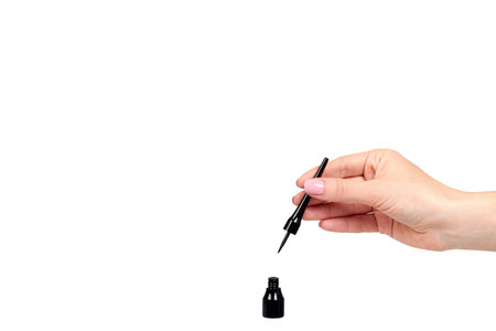 Hand with black liquid pencil, eye makeup brush. Isolated on white background. Copy space template.