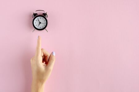 Hand with analog alarm clock composition on pink background. Flat lay, layout and tabletop mockup with copy space.の写真素材