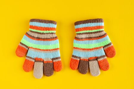 Striped kids winted gloves composition on yellow background. Flat lay, layout and tabletop mockup with copy space.の写真素材