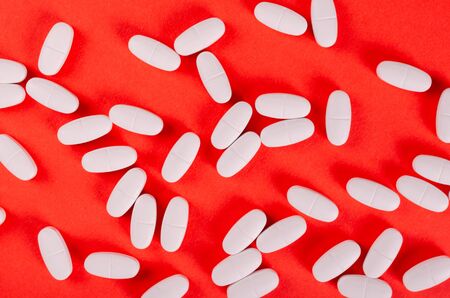 White medical pills composition on red background. Flat lay, layout and tabletop mockup with copy space.の写真素材
